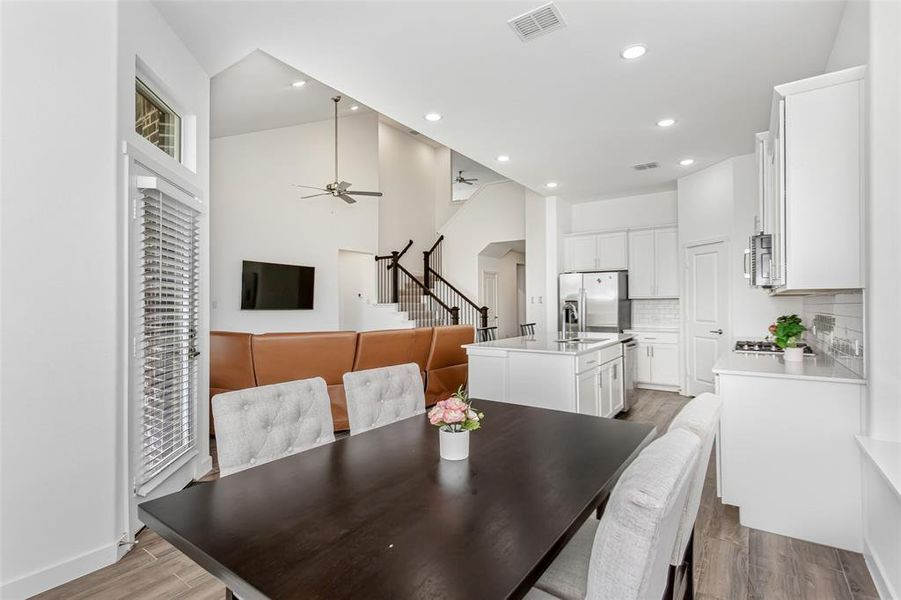 Open-concept living area featuring a kitchen with white cabinetry and stainless steel appliances, a center island, and wood-finish flooring