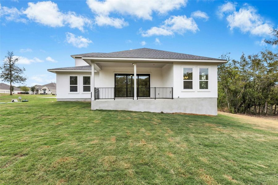 Back of house featuring roof with shingles, a patio, a lawn, and stucco siding Back of house featuring roof with shingles, a patio, a lawn, and stucco siding