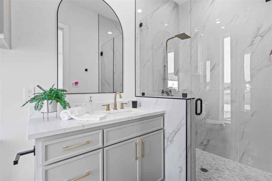 Bathroom with a marble finish shower and vanity