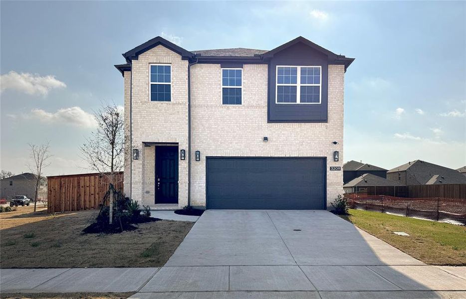 Traditional home with driveway, fence, roof with shingles, a garage, and brick siding