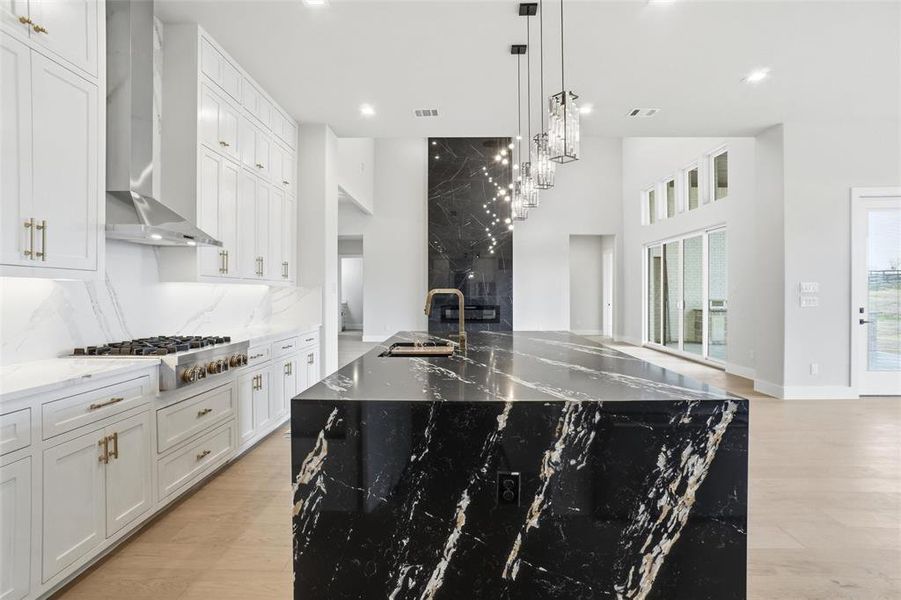Gourmet kitchen highlighted by a waterfall island, gas cooktop, custom cabinetry, and designer lighting overlooking the open living area.