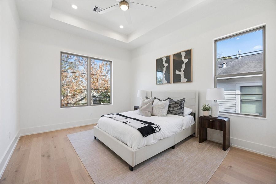Secondary bedroom with a tray ceiling, recessed lighting, ceiling fan, walk-in closet with built-ins and an ensuite bathroom.