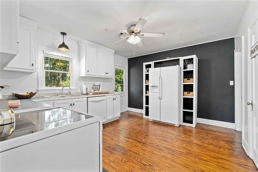 Kitchen with white cabinetry, white appliances, dark wood-type flooring, light countertops, and ceiling fan Kitchen with white cabinetry, white appliances, dark wood-type flooring, light countertops, and ceiling fan