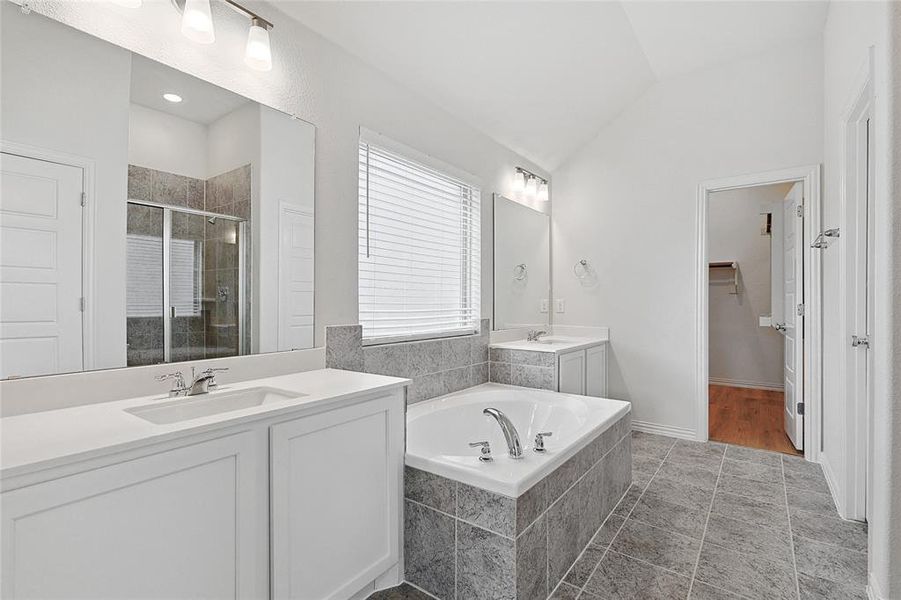 Bathroom with tile floors, lofted ceiling, shower with separate bathtub, and oversized vanity