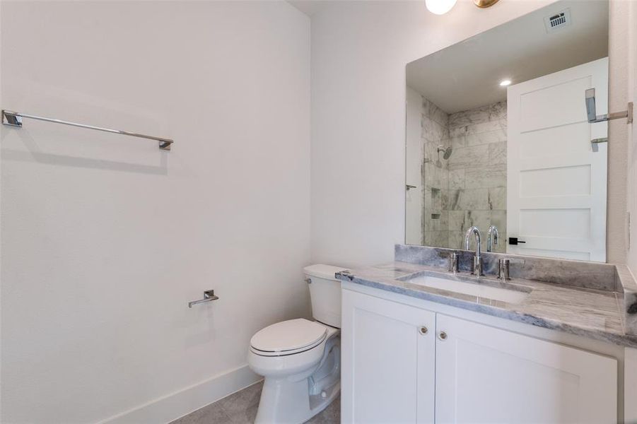 Full bathroom featuring toilet, vanity, visible vents, baseboards, and a tile shower Full bathroom featuring toilet, vanity, visible vents, baseboards, and a tile shower