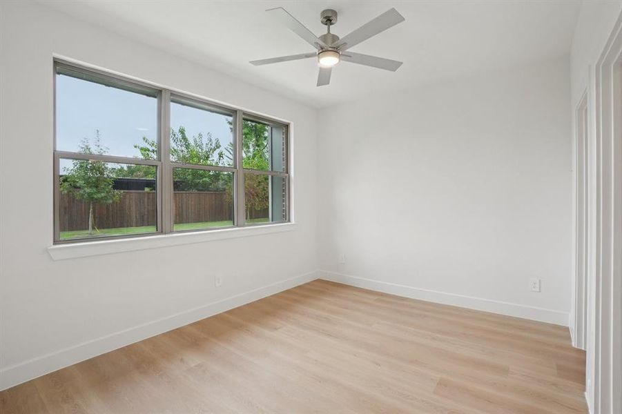 Empty room featuring light wood-type flooring and a ceiling fan