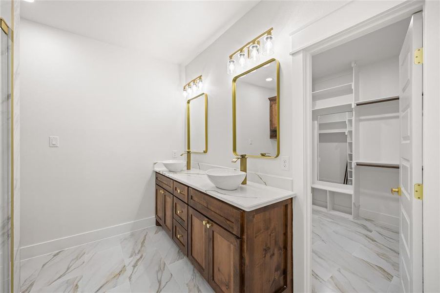 Full bathroom with double vanity, light marble finish flooring, recessed lighting, and a walk in closet