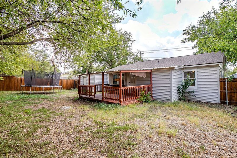 Back of house with a large fenced backyard and covered wooden deck, and brand new roof