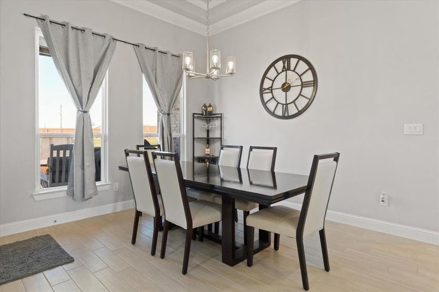 Dining area with baseboards, light wood finished floors, and an inviting chandelier