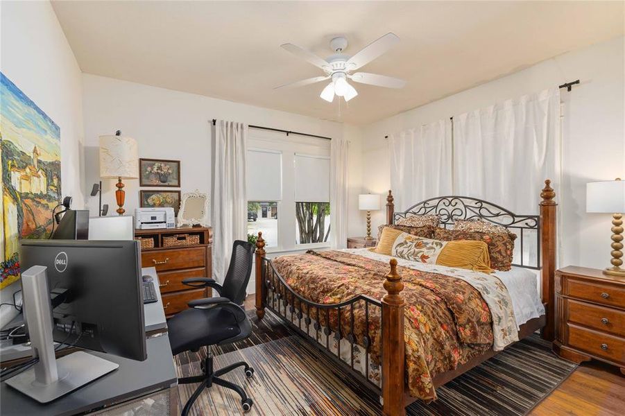 Bedroom featuring hardwood flooring, a ceiling fan with integrated lighting, and white walls