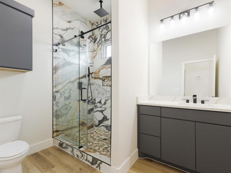 Full bath featuring vanity, a marble finish shower, and light wood-style flooring