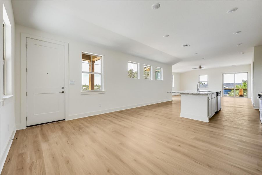 Kitchen with a center island with sink, light wood-style floors, open floor plan, light stone counters, and white cabinets
