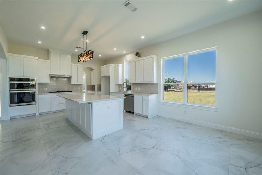 Kitchen featuring light marble finish flooring, white cabinetry, arched walkways, tasteful backsplash, and recessed lighting Kitchen featuring light marble finish flooring, white cabinetry, arched walkways, tasteful backsplash, and recessed lighting