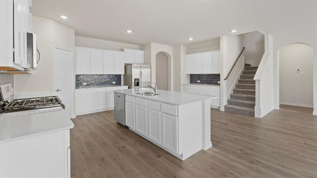 Kitchen featuring arched walkways, tasteful backsplash, white cabinets, appliances with stainless steel finishes, and recessed lighting Kitchen featuring arched walkways, tasteful backsplash, white cabinets, appliances with stainless steel finishes, and recessed lighting