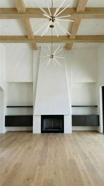 Unfurnished living room with a fireplace, coffered ceiling, and light wood-style flooring