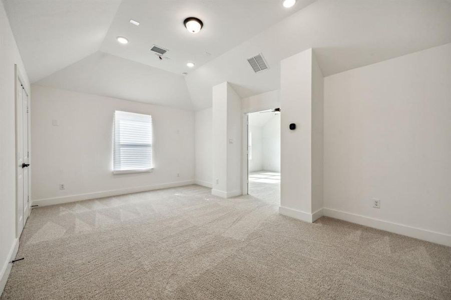 Unfurnished bedroom featuring light carpet and vaulted ceiling