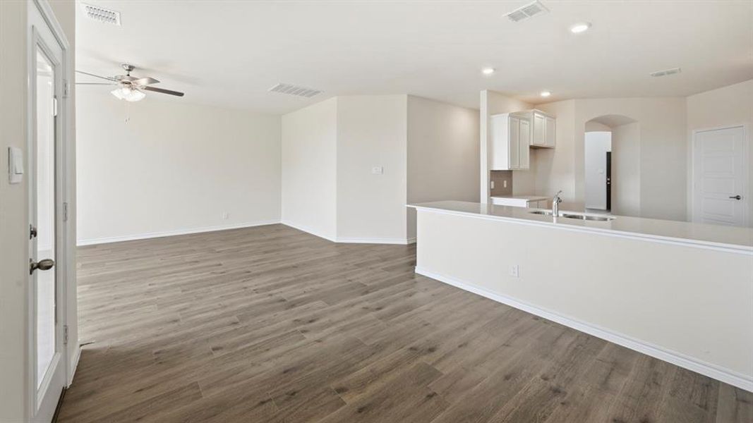 Unfurnished living room featuring dark wood-style flooring, arched walkways, a ceiling fan, and recessed lighting