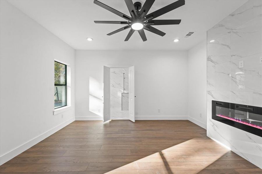 Unfurnished living room featuring ceiling fan, dark wood-type flooring, and a tiled fireplace