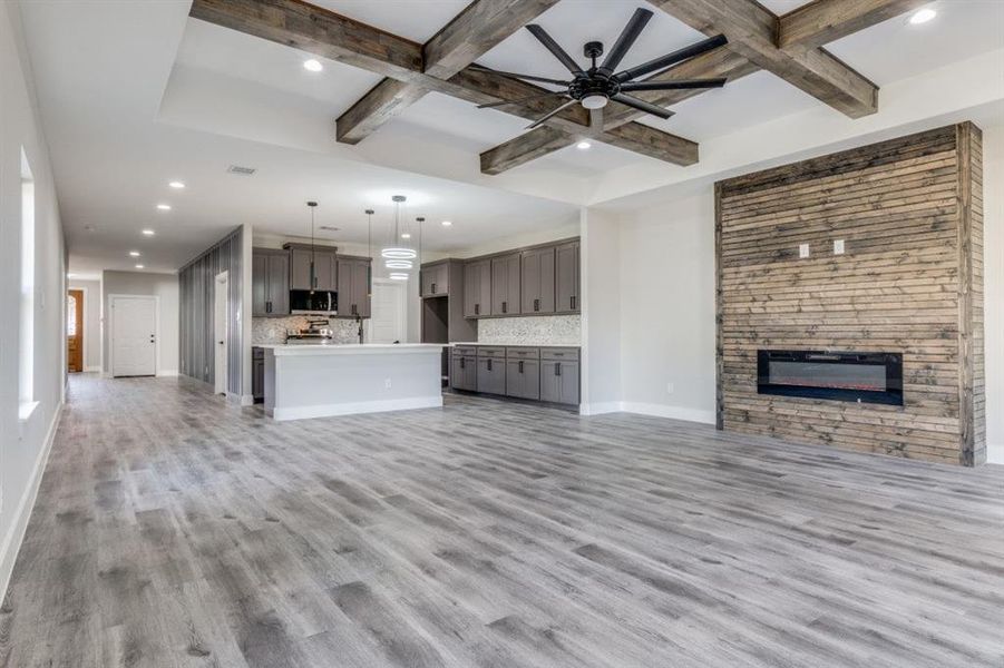 Unfurnished living room featuring beam ceiling, a fireplace, light hardwood / wood-style floors, and coffered ceiling