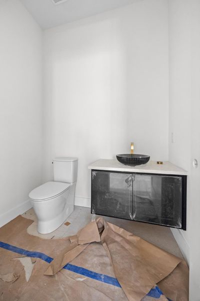 Modern bathroom featuring a floating black vanity with a light-toned countertop, a black vessel sink, and a gold-toned wall-mounted faucet