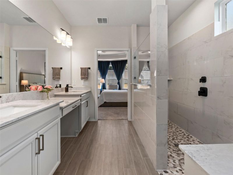 Bathroom with healthy amount of natural light, a walk in shower, connected bathroom, and double vanity