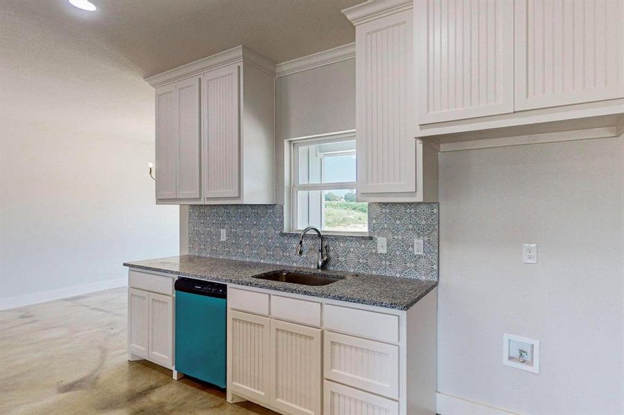 Kitchen featuring sink, tasteful backsplash, dark stone countertops, dishwasher, and white cabinets