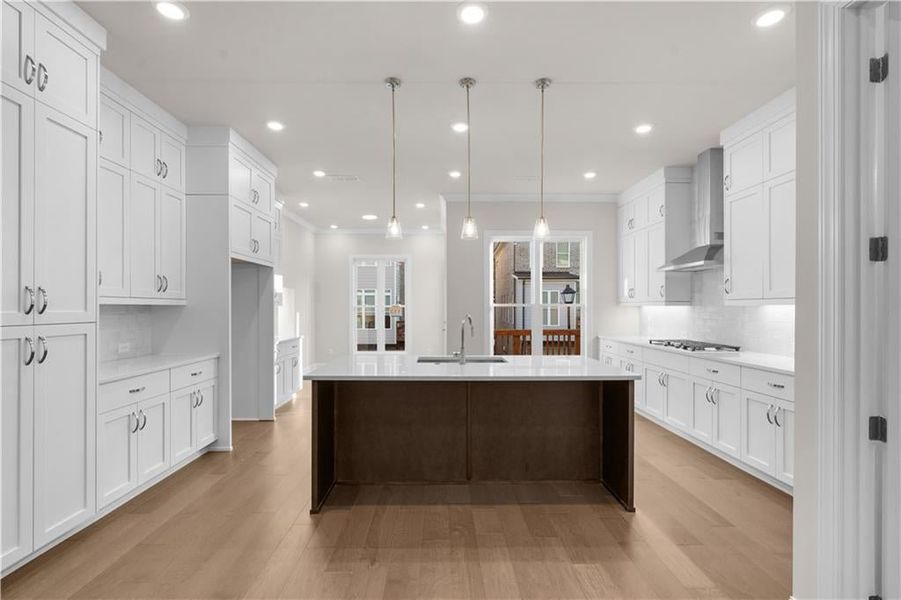 Kitchen featuring tasteful backsplash, decorative light fixtures, white cabinets, recessed lighting, and light wood-style floors