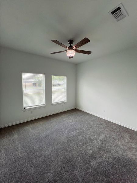 Unfurnished room with baseboards, a ceiling fan, dark colored carpet, and visible vents Unfurnished room with baseboards, a ceiling fan, dark colored carpet, and visible vents