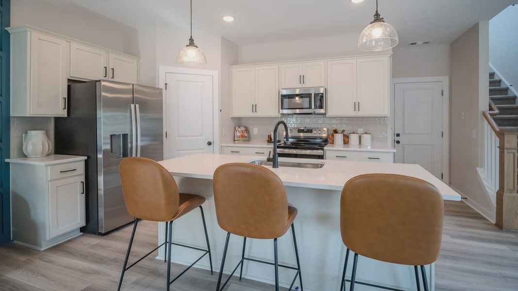 Kitchen with tile backsplash, quartz countertops, and pendant lighting
