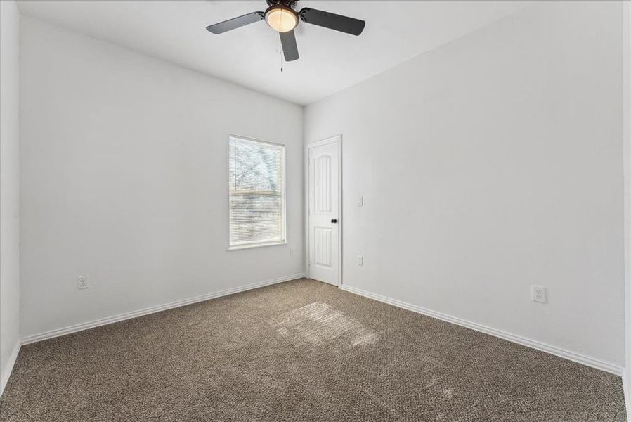 Carpeted empty room with ceiling fan and baseboards