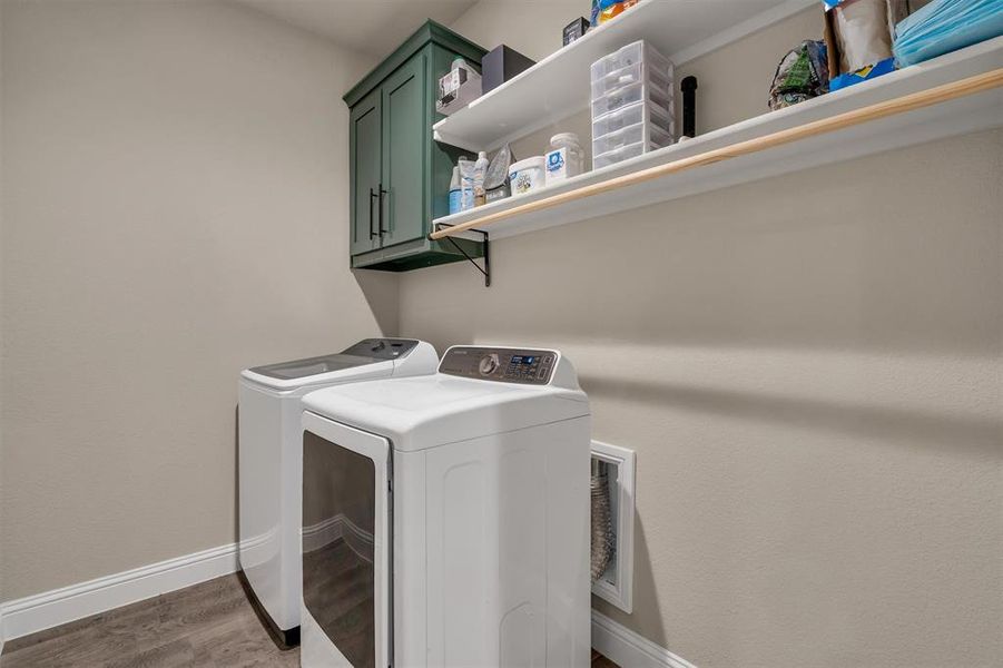Laundry area with separate washer and dryer, cabinet space, and light wood-style floors