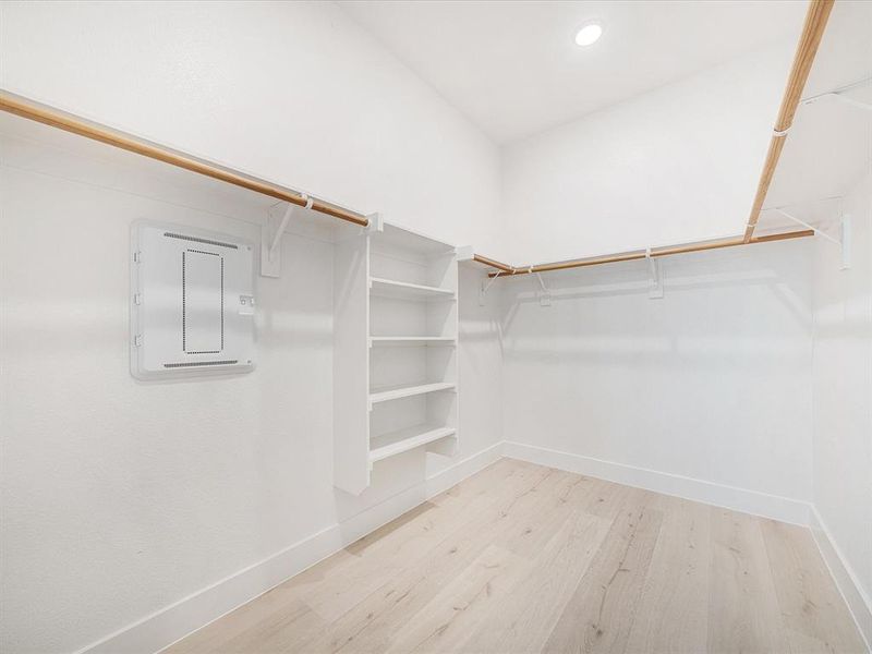Walk in closet with light wood-type flooring and electric panel