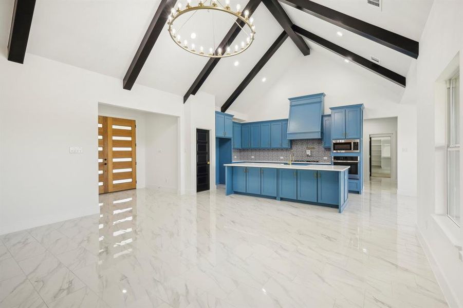 Kitchen with beamed ceiling, decorative backsplash, blue cabinetry, and appliances with stainless steel finishes