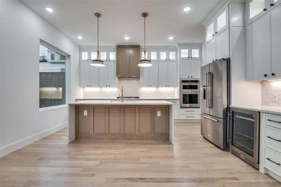Kitchen featuring decorative backsplash, stainless steel appliances, beverage cooler, light countertops, and recessed lighting