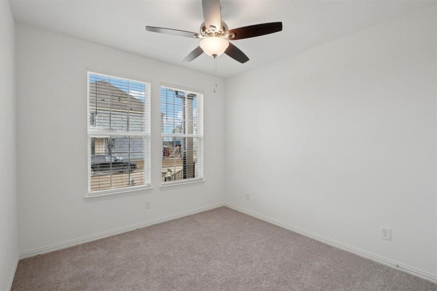 Empty room featuring ceiling fan and light carpet