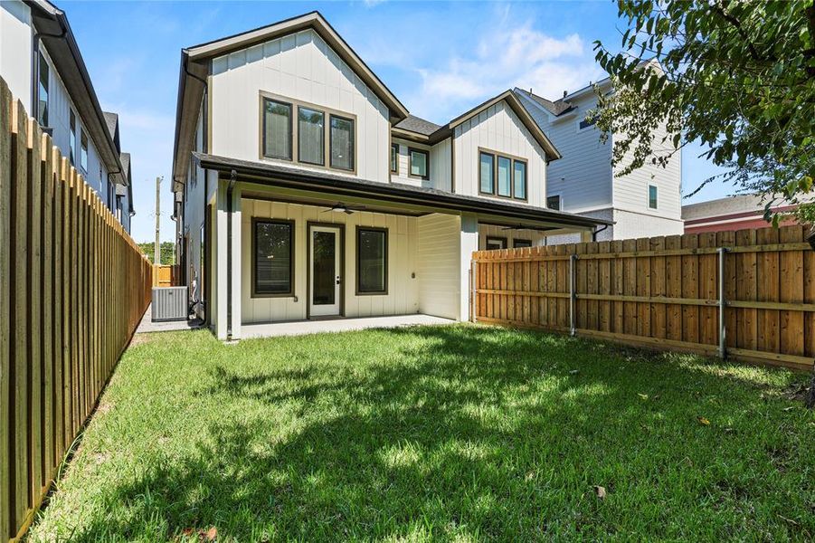 Back of house with ceiling fan, board and batten siding, a fenced backyard, and a patio Back of house with ceiling fan, board and batten siding, a fenced backyard, and a patio