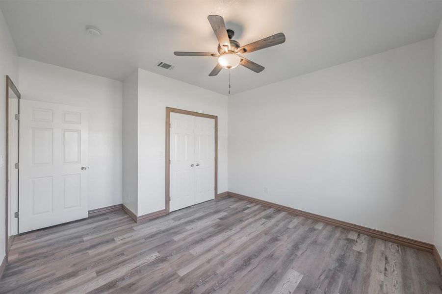 Unfurnished bedroom with a closet, visible vents, baseboards, and wood finished floors