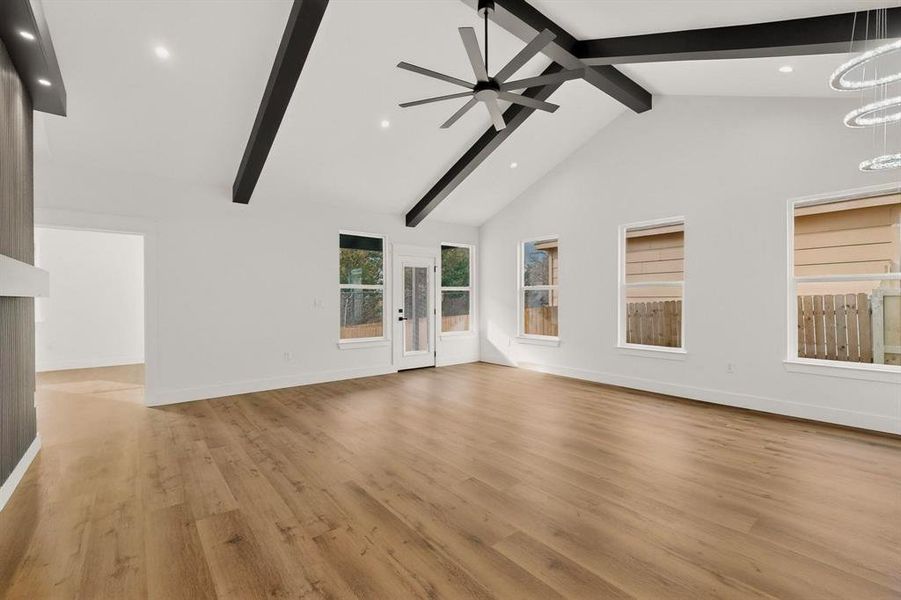 Unfurnished living room with light wood-style flooring, ceiling fan, french doors, and hanging lights Unfurnished living room with light wood-style flooring, ceiling fan, french doors, and hanging lights