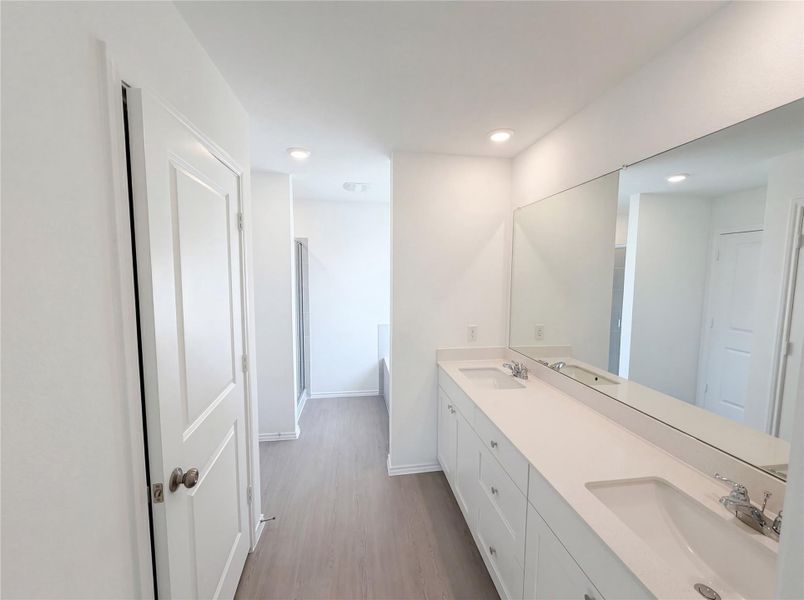 Full bath with double vanity, light wood-style floors, recessed lighting, and a stall shower