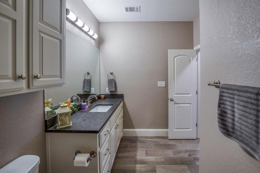 Guest bathroom with vanity, toilet, and wood-type flooring