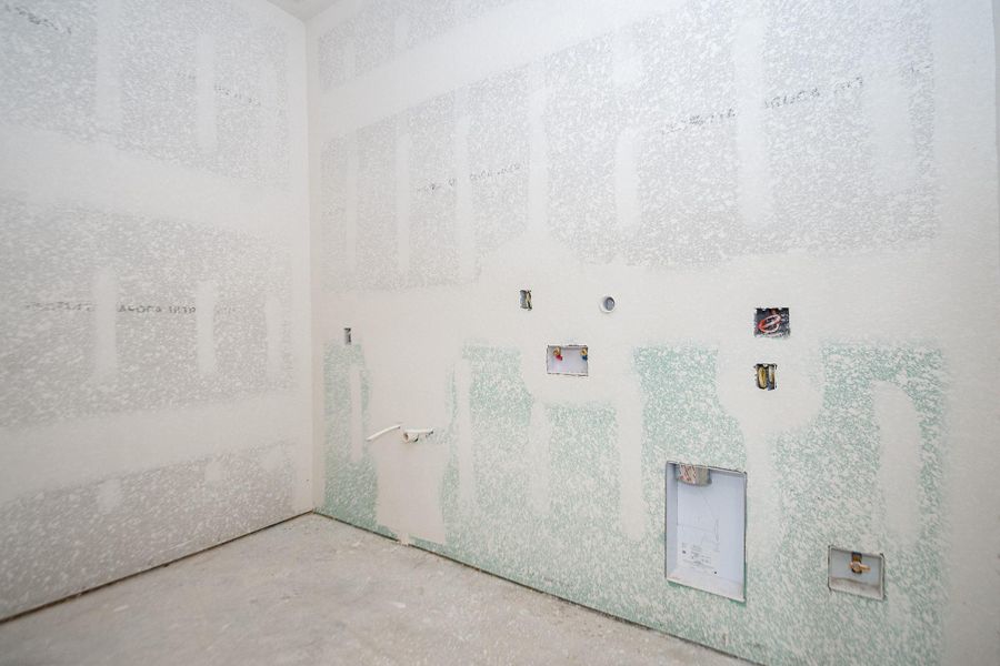 Spacious laundry room with utility connections ready for customization, featuring freshly installed drywall. Spacious laundry room with utility connections ready for customization, featuring freshly installed drywall.