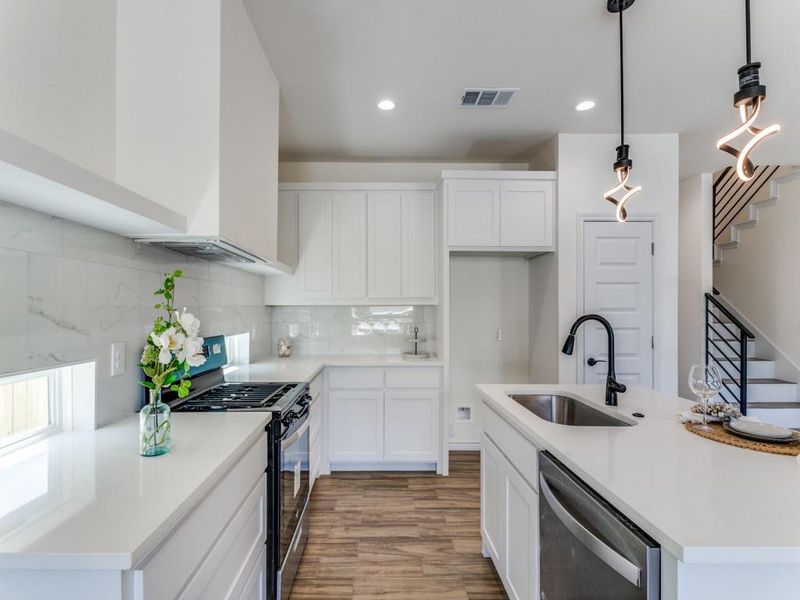 Kitchen featuring white cabinets, hanging light fixtures, hardwood / wood-style flooring, sink, and stainless steel appliances