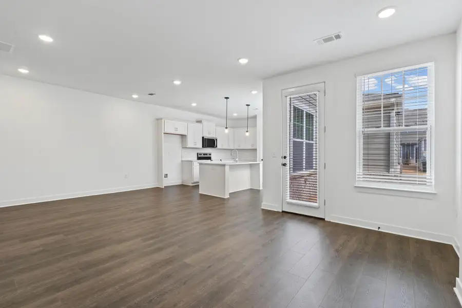 Open-concept living area featuring wood-finish flooring, recessed lighting, and a white color palette