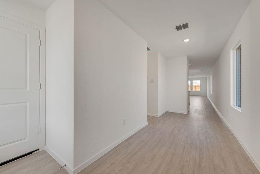 Hall with light wood-style floors and recessed lighting