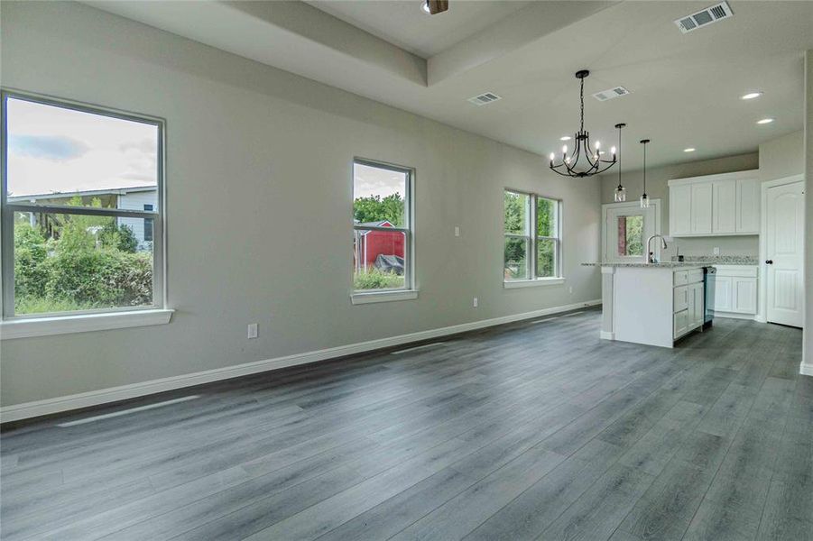 Unfurnished living room featuring hardwood / wood-style flooring, a raised ceiling, sink, and an inviting chandelier