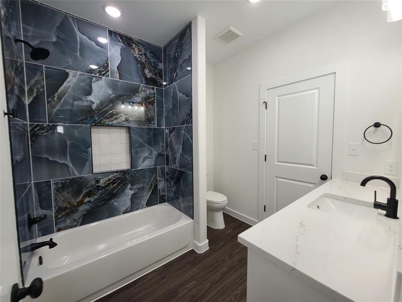 Full bathroom with vanity, toilet, hardwood / wood-style flooring, and tiled shower / bath