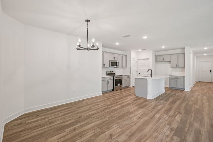 Luxurious kitchen with sleek grey cabinets, elegant chandelier, and premium wood flooring in Spring Hill.