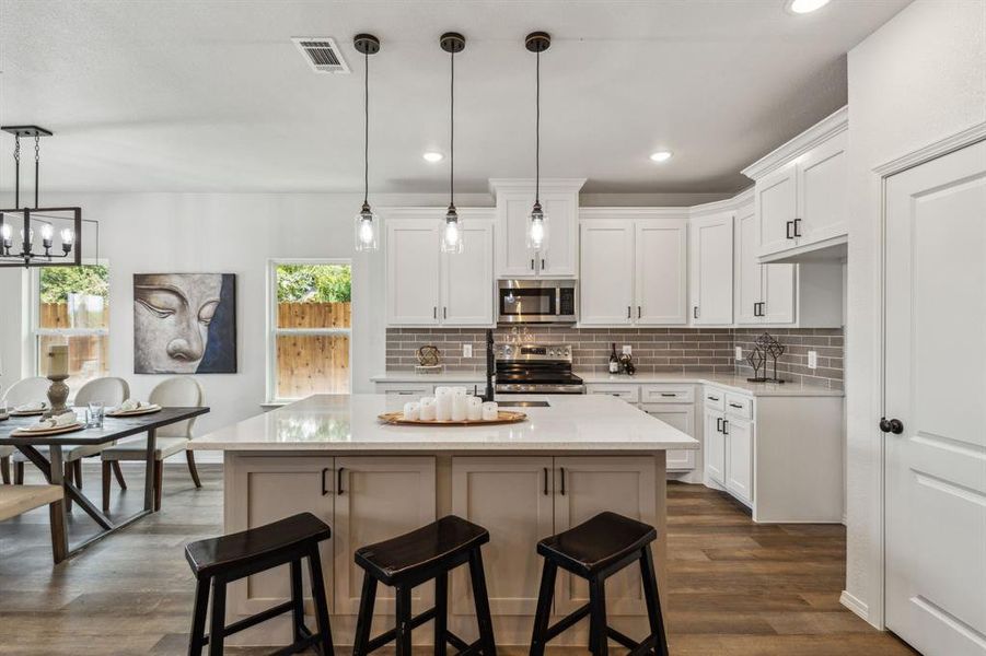 Kitchen featuring white cabinets, decorative light fixtures, dark hardwood / wood-style flooring, and appliances with stainless steel finishes