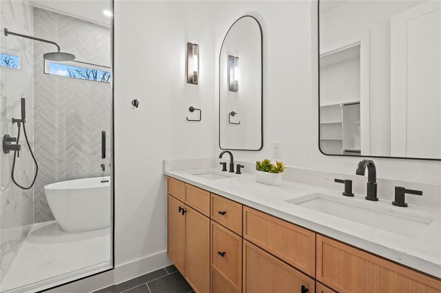 Full bath with double vanity, a tile shower, a freestanding tub, and dark tile patterned flooring