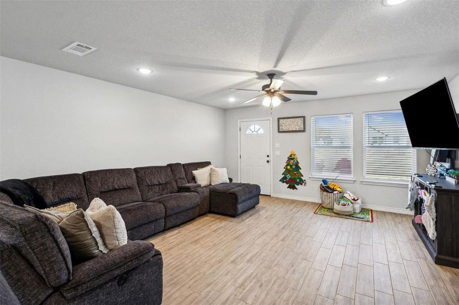 Living room with ceiling fan, light hardwood / wood-style flooring, and a textured ceiling